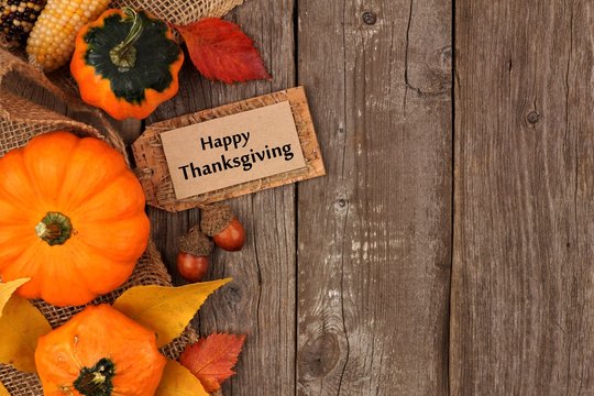 Happy Thanksgiving gift tag with side border of colorful leaves and pumpkins over a rustic wood background