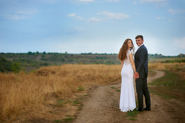 bride and groom walking on the road in a field