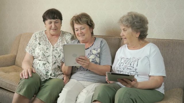 Elderly women look at photos using digital tablets
