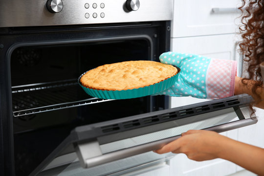 African American woman with hot cake near oven in kitchen