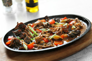 Tasty ragout with mushrooms in cast iron dish on wooden cutting board