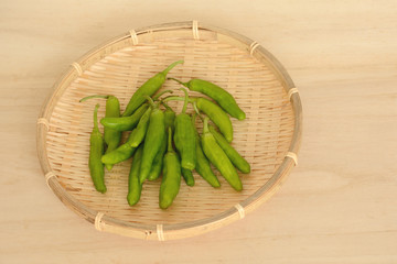 ザルに入ったシシトウ　木目背景