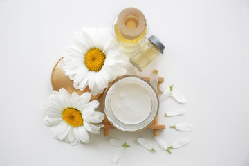Obraz na płótnie Canvas Cosmetic cream and chamomile flowers on white background