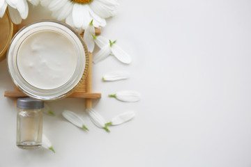 Fototapeta na wymiar Cosmetic cream and flower petals on white background