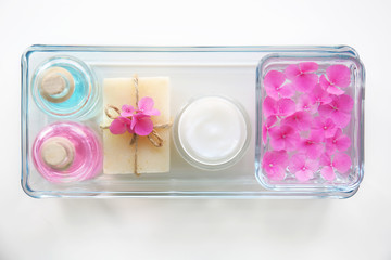 Hygienic cosmetic products and flower petals on white background