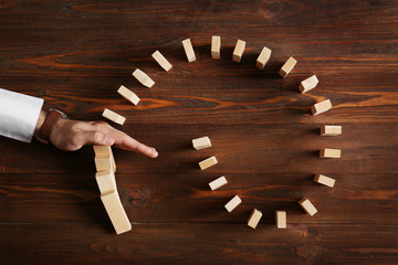 Male hand stopping domino effect on wooden table