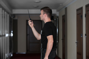 Security man standing indoors and using portable radio