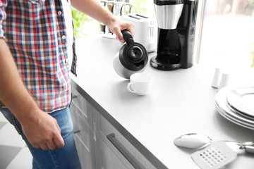 Fototapeta na wymiar Man making morning coffee in kitchen