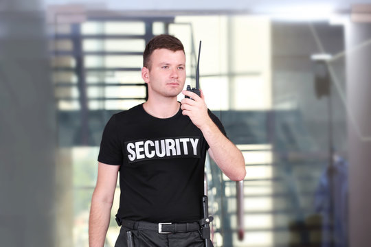 Security man standing beside stairs and using portable radio