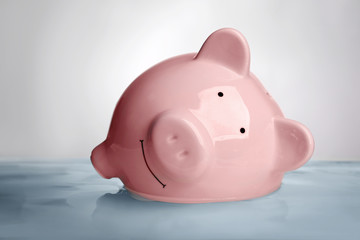 Pink piggy bank in water on light background. Saving water concept