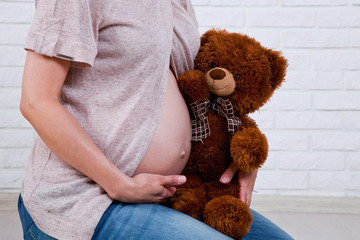 belly of a pregnant woman with a teddy bear