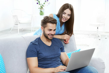 Beautiful young couple using laptop at home