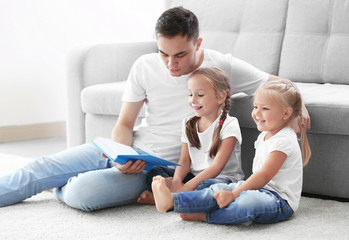 Happy father with daughters reading book