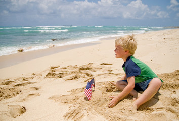 Fototapeta na wymiar Little boy with an American flag on the beach
