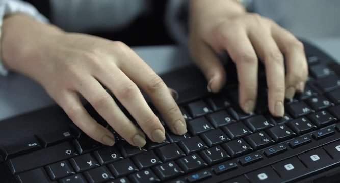 4K: Nahaufnahme weiblicher H&auml;nde die auf einer schwarzen Tastatur schreiben.