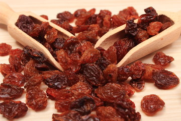 Brown raisins with spoon on wooden table, healthy eating
