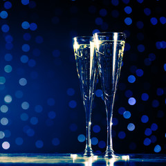Two glasses of champagne on dark bokeh background