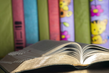 Open book, stack of colorful hardback books on light table. Back to school. Copy space for text