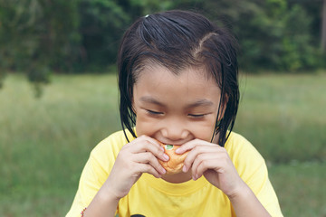 Cute girl is eating bread. Tasty bread makes her happy.