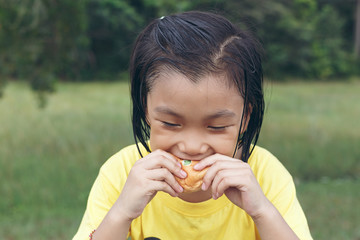 Fototapeta premium Cute girl is eating bread. Tasty bread makes her happy.