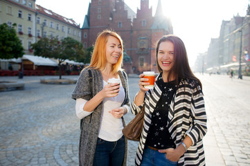 Morning. Nice young women standing on the square of the beautiful European city.