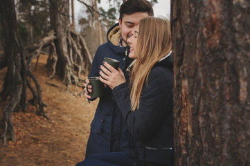 Fototapeta na wymiar lifestyle capture of happy couple drinking hot tea outdoor on cozy warm walk in forest