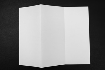 Trifold white template paper on black background .