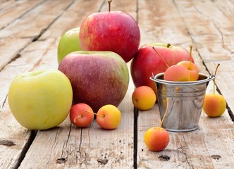 Variety of apples on a wooden table in small metal buckets
