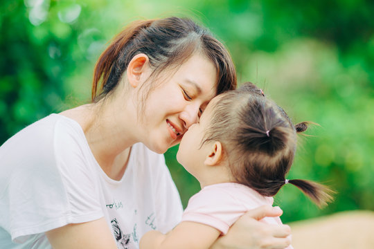 1 year 9 months baby feeling happy and smiles when she hug and kissing with her mother in the garden : Selective focus.