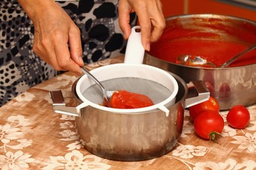 Woman making ketchup, tomatoes boiled to mush pressed through strainer