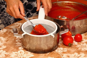 Woman making ketchup, tomatoes boiled to mush pressed through strainer
