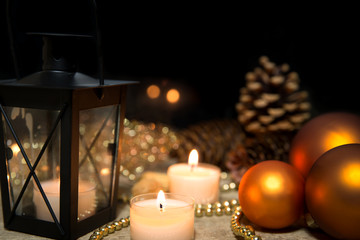 christmas balls, candles, a lantern and pearls on wooden table