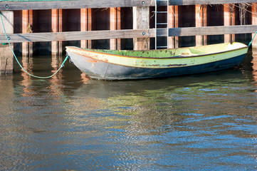 Old iron rowing boat moored at a wooden quayside