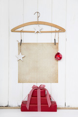 Weihnachten Hintergrund mit Schild in beige auf Holz Hintergrund weiß und Geschenke in rot kariert mit Dekoration.