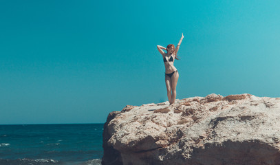 young girl in black bikini standing at Rock near sea, crete, Greece