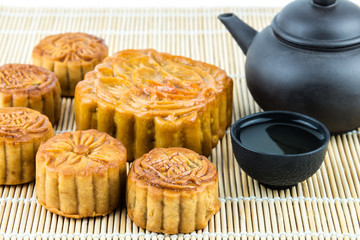 Mooncake and tea, food and drink for Chinese mid autumn festival. Traditional mooncakes on table setting with teapot.