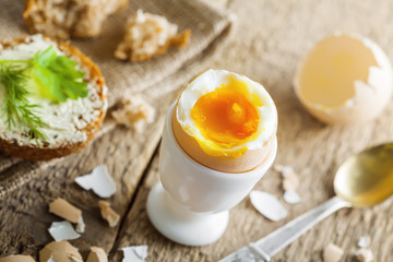 Perfect soft boiled egg and open bread sandwich with butter and dill on a table. Traditional food for healthy breakfast.