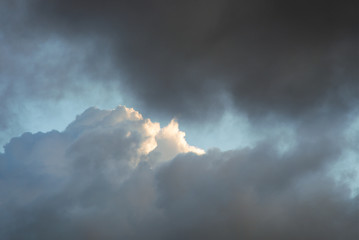The tragic dark cloud cover other brightly lit light clouds.