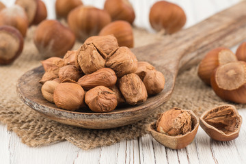 Hazelnut in wooden spoon ins old white wooden table.