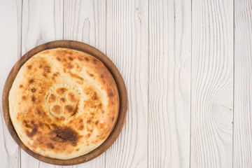 Uzbek flat cake on the board and an old white wooden table.