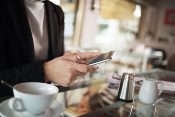 Fototapeta na wymiar Businesswoman texting with her mobile during a coffee break