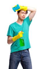 Housekeeping concept. Studio portrait of tired young man in gloves cleaning glass with wisp and sprayer. Isolated on white.