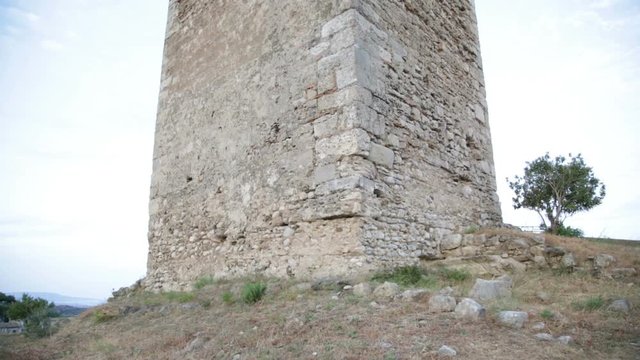 Antica torre greca vecchia e danneggiata medievale. Vista tilt dal basso verso l'alto. 
