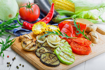 Grilled vegetables meal and ingredients on a table. Tomato, corn, eggplant, mushroom, bell pepper, marrow and onion prepared on a barbecue. Healthy food.