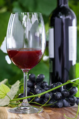 Glass and a bottle of vintage red wine. Alcohol drink on a table. Outdoor shot.