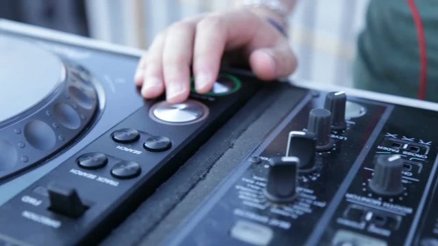 Mani del deejay sul mixer durante una festa in una discoteca diurna.