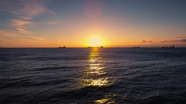 Aerial view over sea water, cargo ships and beautiful sunrise