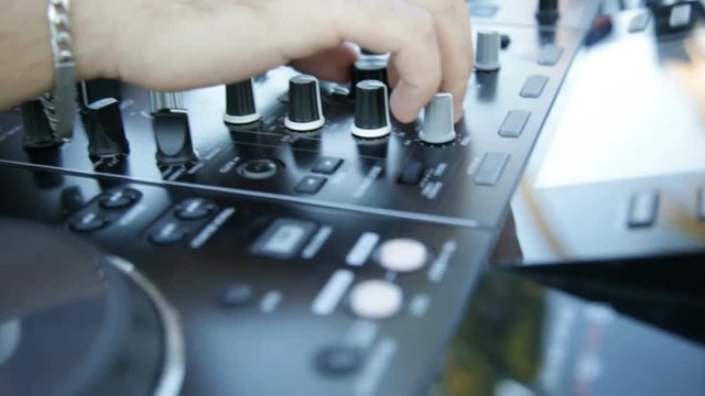 Mani del deejay sul mixer che sta suonando ad una festa diurna. 