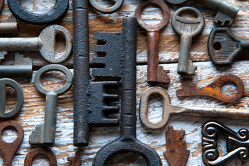 Many rusty keys and padlocks on white wood