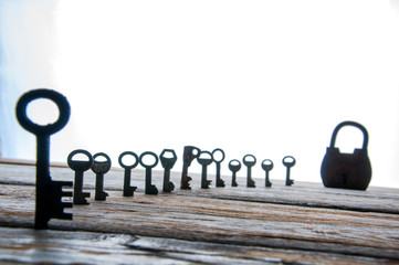 Old rusty keys and padlock on white wooden table